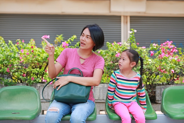 Asian mother and her daughter sitting at bus station 