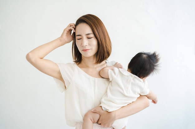 Madre asiatica che tiene in braccio un bambino e sembra stanca