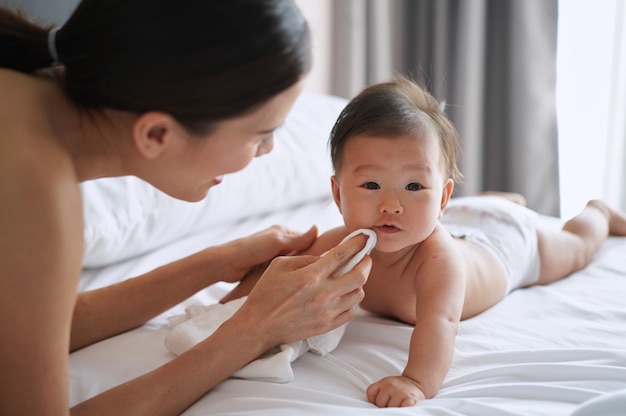 アジアの母親は、おむつを使って生まれたばかりの赤ちゃんの口をやさしく拭きます。