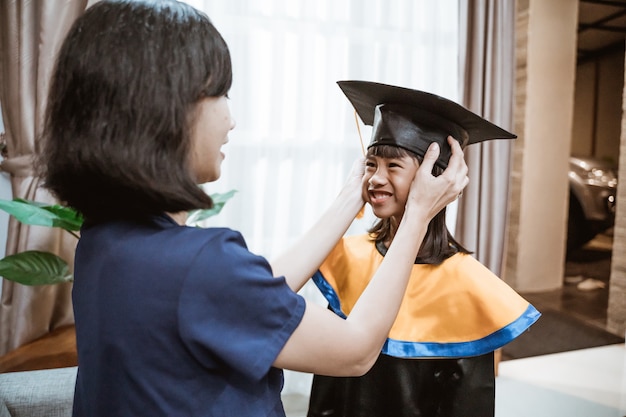 Asian mother and kid preparing on her kinder graduate day at home