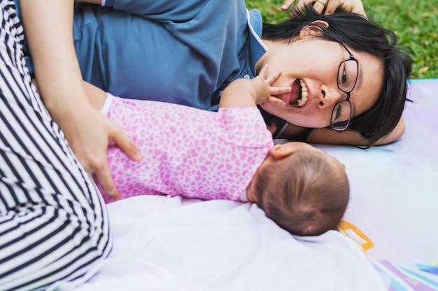 Asian mother playing and taking care of  baby at park