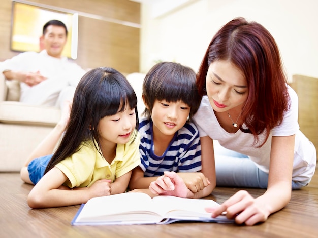 アジアの母親が2人の子供と一緒に本を読んでいる