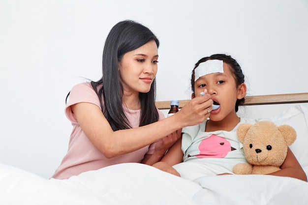 Asian mother take care sick daughter on bed