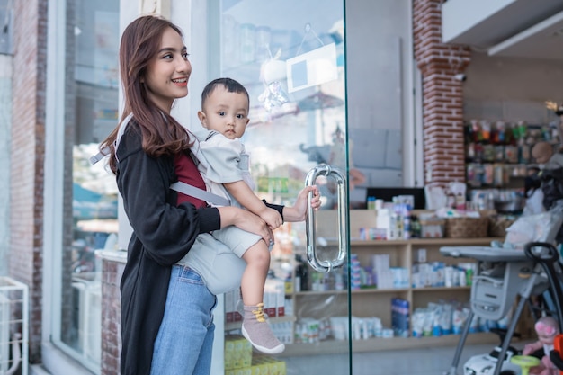 Foto madre asiatica con il suo bambino che entra nel centro commerciale