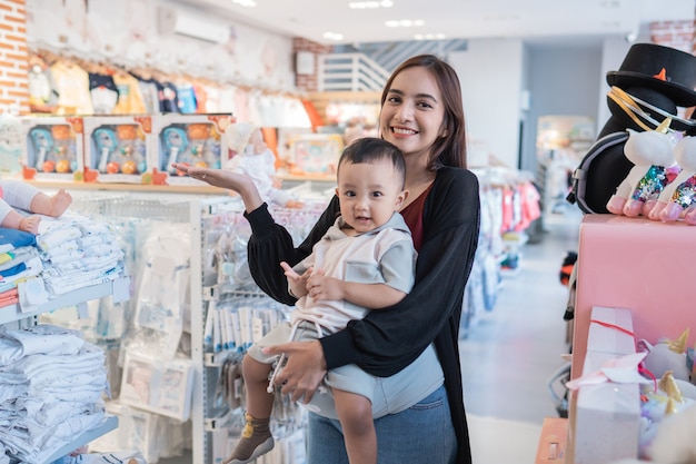 Asian mother with her toddler boy shopping in the baby shop