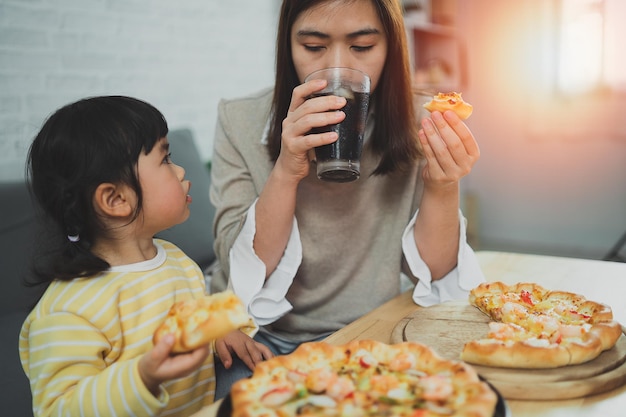 アジアの母親と子供たちは家で活動します母親は子供たちのためにピザを食べようとしています