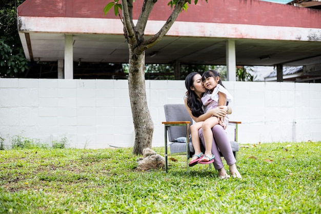 Mamma e figlia asiatiche fanno attività divertenti insieme sul campo in erba nel giardino di casa. concetto di famiglia amorevole felice.