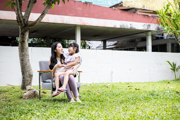 아시아계 엄마와 딸은 집 정원에 있는 잔디밭에서 함께 재미있는 활동을 합니다. 행복한 사랑의 가족 개념입니다.