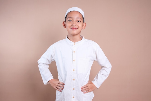 Asian Muslim boy looking at camera with hand on waist and smiling