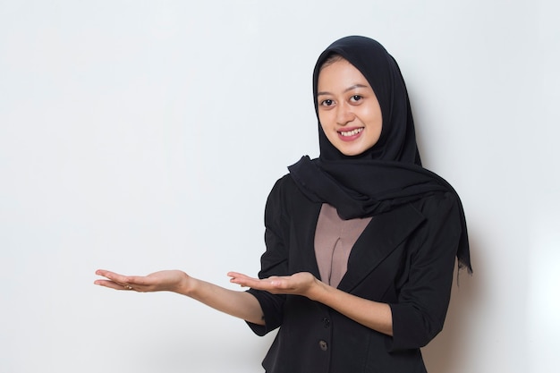 Asian muslim business woman pointing fingers to different directions copy space for advertisement