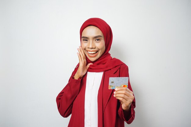 Asian Muslim businesswoman in red casual holding a credit card isolated by the white background