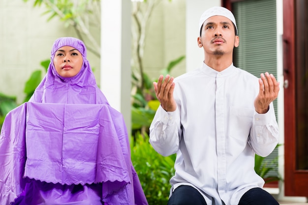 Asian muslim couple, man and woman, praying at home