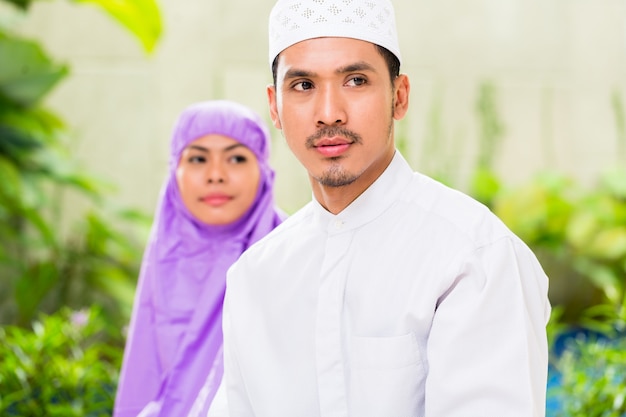 Asian Muslim couple, man and woman, praying at home