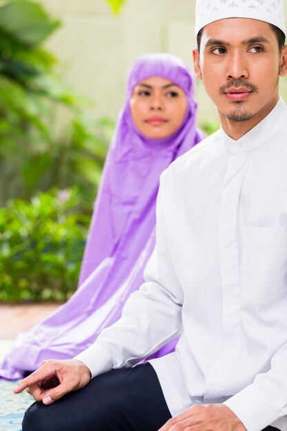 Asian Muslim couple, man and woman, praying at home