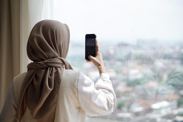 Asian Muslim girl in casual clothes is using a smartphone taking pictures