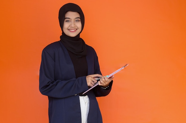 서류 문서가 있는 클립보드를 잡고 웃고 있는 아시아 이슬람 여성