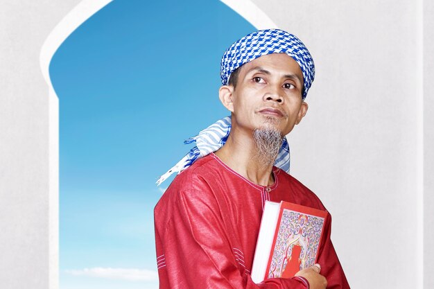 모스크에 코란을 들고 앉아 아시아 무슬림 남자