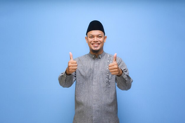 Photo asian muslim man smiling to give greeting during ramadan and eid mubarak celebration