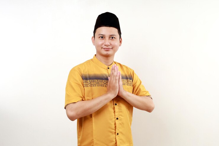 Photo 亞洲穆斯林男子在白色的背景上微笑,在齋戒節和節日慶祝期間致敬