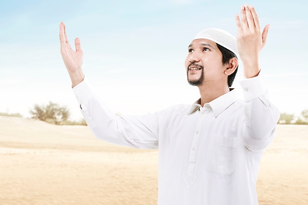 사진 제기 손을 동안 서서 푸른 하늘 배경으로기도하는 아시아 무슬림 남자
