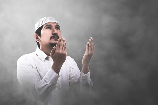 아시아 이슬람 남자가 손을 들고 밝은 배경으로 기도하면서 서 있다