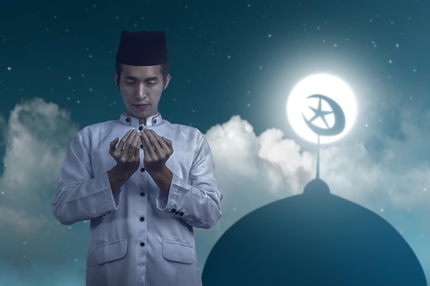 아시아 이슬람 남자가 손을 들고 밤 장면을 배경으로 기도하면서 서 있다