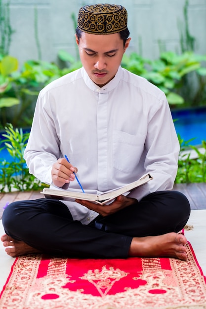 Asian Muslim man studying Koran or Quran