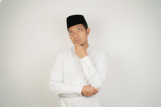 Asian Muslim man thinking about something touching his chin wearing Arab costume at copy space