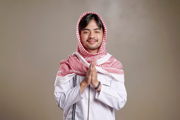 Foto uomo musulmano asiatico che indossa kufiya sorridendo per salutare durante le celebrazioni del ramadan e dell'eid