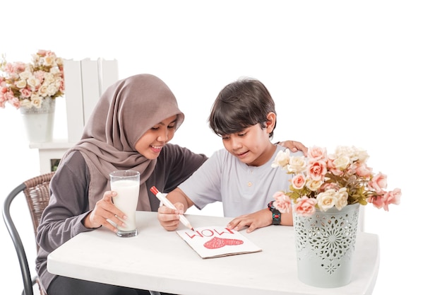 Asian muslim mother is serving her son a glass of milk while studying