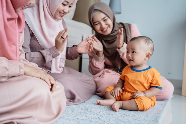 Asian muslim mother with her friends enjoy playing with her son when sitting on the floor