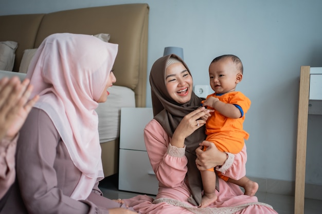 Asian muslim mother with her friends enjoy playing with her son when sitting on the floor