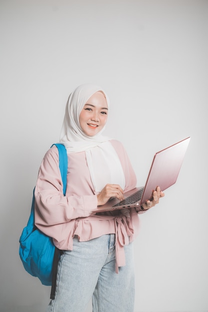 Asian muslim student holding laptop in front of white isolated background