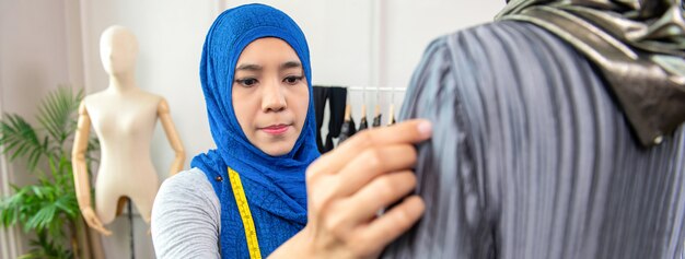 Foto progettista musulmano asiatico della donna che lavora nel suo negozio di sarto