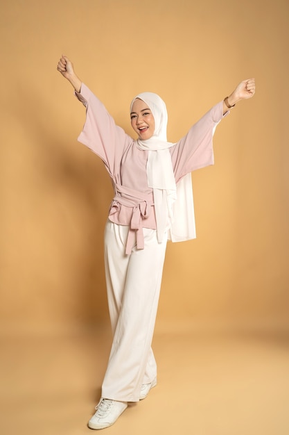 Asian muslim woman euphoric raising arm 