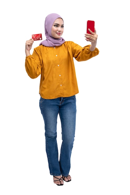 Asian Muslim woman in a headscarf using a mobile phone while holding a credit card