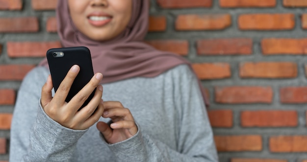 Азиатская мусульманская женщина, держащая смартфон