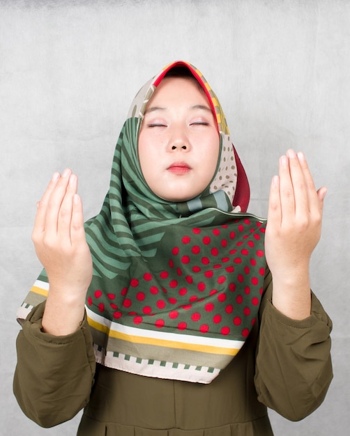 Asian Muslim woman praying with both hands raised