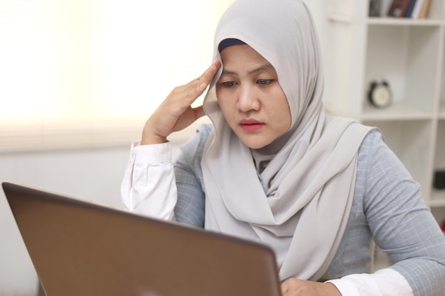 Asian muslim woman sad and frustrated to see her business report on laptop businesswoman failure