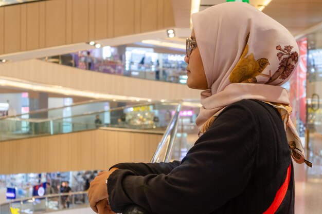 An Asian Muslim woman standing alone in a shopping mall