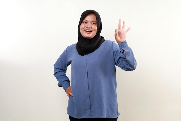 Asian muslim woman standing while making okay hand gesture and looking at the camera