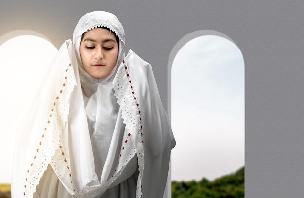 Asian muslim woman in veil in praying position salat on the\
mosque