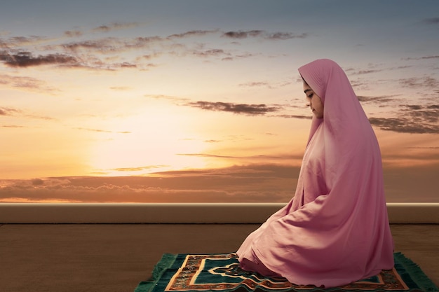 祈りの位置のサラッでベールに包まれたアジアのイスラム教徒の女性