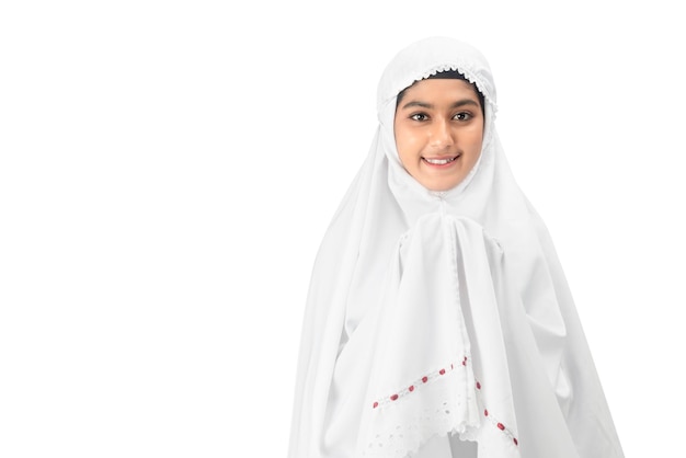 Asian Muslim woman in a veil standing while raised hands and praying isolated over white background