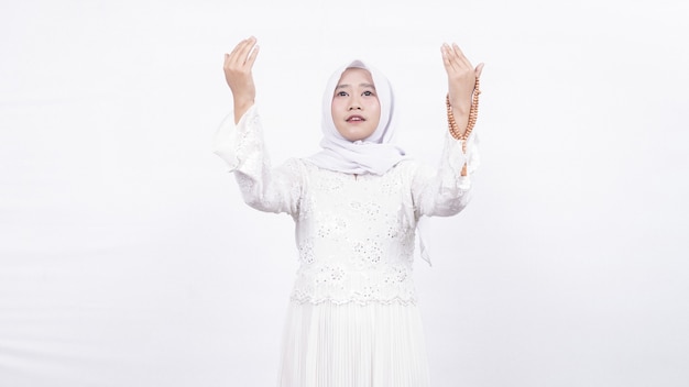 Asian muslim woman wearing prayer beads pray in white