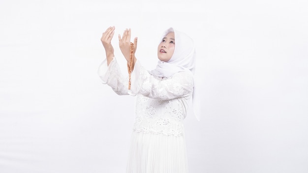 Asian muslim woman wearing prayer beads pray in white