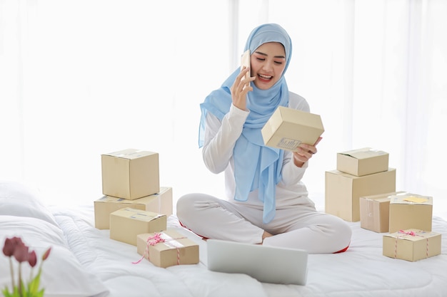 침대에 상자가 많은 아시아 무슬림 여성