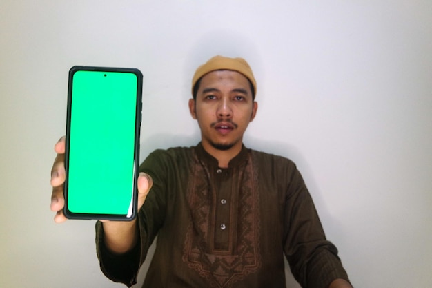 Asian muslim young man showing smartphone with green screen