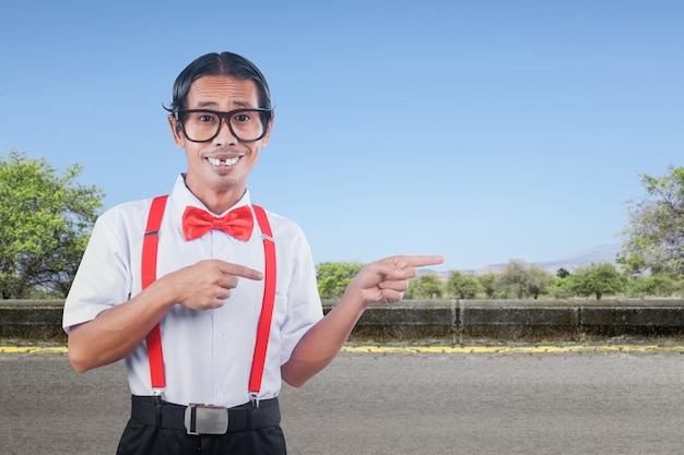 Asian nerd with an ugly face pointing something on the street