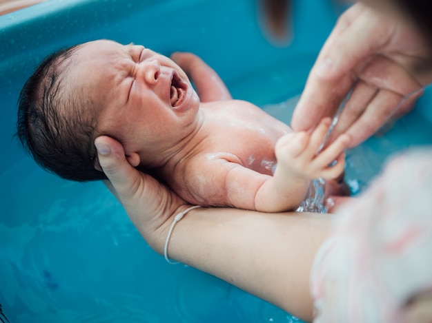 写真 アジア人の新生児が母親によってお風呂を楽しんで生まれました。